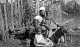 African American woman with three children and a dog in front of a wooden fence in rural Wilcox County, Alabama.