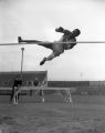 Ed Burke is caught in mid-air as he jumps over the high jump bar, 1939