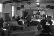 Norman Lumpkin speaking to an audience in a small wooden church building in Prattville, Alabama.