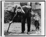 [Martin Luther King, Jr., pulls up cross that was burned on lawn of his home, as his son stands next to him, Atlanta, Georgia]