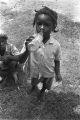 Little girl drinking from a glass soda bottle.