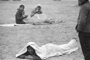 African American girl lying under a quilt on the grass in the George Washington Carver Homes neighborhood in Selma, Alabama, during the "Berlin Wall" demonstrations.