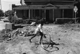 Boy playing in the street with bicycle wheel.