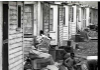 Children at play around trash at back of a row of sub-standard dwellings