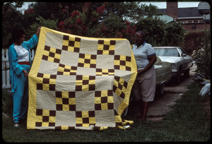 Fabric arts: Ruby Merritt. Tanya Frazier (left) and Ruby Merritt hold up Merritt's brown and yellow Nine Patch quilt.