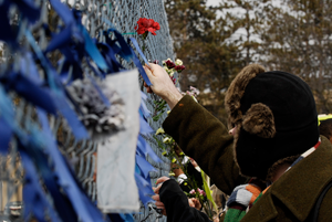 Thumbnail for Justice for Jason rally at UMass Amherst: protesters in support of Jason Vassell placing flowers in a chain link fence