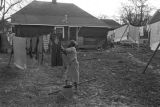 Mrs. Rosa Lee Turner hanging laundry on a clothesline in the dirt yard behind her house in Montgomery, Alabama.