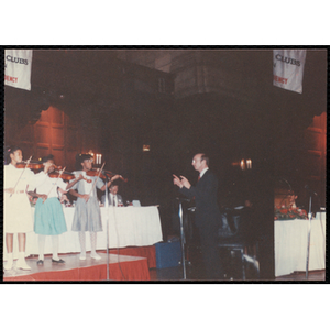 Three girls playing violin and a man conducting at the "Recognition Dinner at Harvard Club"