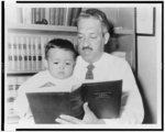 [Thurgood Marshall, half-length portrait, facing left, holding and reading to his son, Thurgood, Jr., 22 months old]