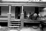 Four young men playing cards on the front porch of a wooden house in Newtown, a neighborhood in Montgomery, Alabama.