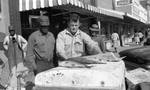 African American man buying fish from white man: Image 1