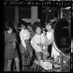 Flori Roberts Cosmetics makeup artist demonstrating products to women shoppers at May Co. store in Los Angeles, Calif., 1970