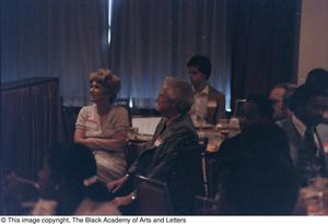 Photograph of people in formal wear sitting at dining tables