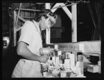 A Negro woman at North American Aviation uses an electric hand drill to drill holes in a sheet metal assembly prior to riveting