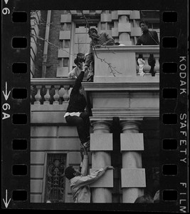 Students pull up another student up to balcony of Boston University administration building to join sit-in