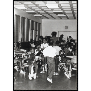 Roxbury Boys and Girls Club members sit and stand around tables, holding flowers in their hands