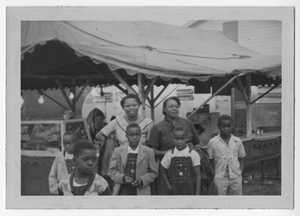 Photograph of an African American family in front of a booth at the fair, Manchester, Georgia, 1953