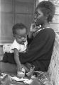 Young woman holding a baby while sitting on the porch of a house in Little Korea, a neighborhood in Birmingham, Alabama.