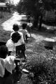 Woman leading children toward a dirt road in Newtown, a neighborhood in Montgomery, Alabama