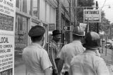 Police officers speaking to an African American man in front of a business down the street from 16th Street Baptist Church in Birmingham, Alabama, after the church was bombed.