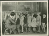 Woman checking mouths of elementary school children