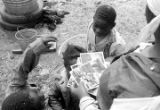 Wife and children of John Nixon standing in their yard in Autaugaville, Alabama, looking at photographs of themselves.