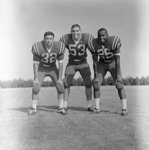 Three football players squatting, 2