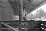 Thumbnail for Young man standing in a crate of cotton outside a cotton gin near Mount Meigs in Montgomery County, Alabama.