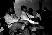 Men seated along a wall, listening to a speaker during a meeting at the office of the Autauga County Improvement Association in Prattville, Alabama.