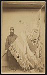 [Unidentified soldier in Union uniform displaying tattered 7th Connecticut Infantry Regiment flag]