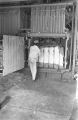 Man removing a bale of cotton from a baler in a gin near Mount Meigs in Montgomery County, Alabama.