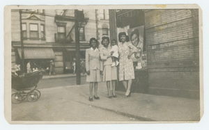 Three women and toddler on street corner.