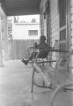 Little boy sitting in a chair on the front porch of a house in Little Korea, a neighborhood in Birmingham, Alabama.