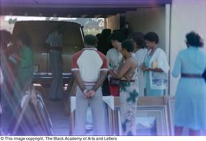 Photograph of various people standing in a car garage full of James Edward Kemp's art