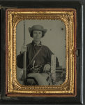 [Unidentified soldier in Confederate uniform with rifle musket, revolver, side knife, canteen, and sign reading Jeff Davis and the South!]