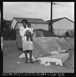 Woman and baby on sidewalk in Watts, Los Angeles (Calif.)