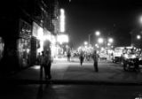 People on a sidewalk in the business district of Harlem at night.