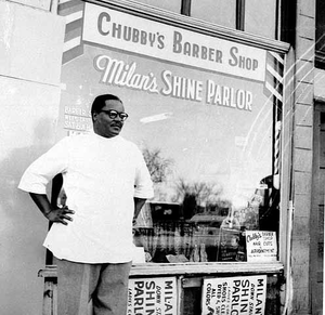 Sylvester "Chubby" Young in front of his barber shop, Minneapolis.