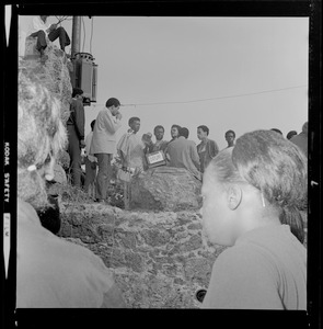 View of speakers addressing the crowd at Elma Lewis Playhouse in Franklin Park, one holding a sign reading "DRUM"