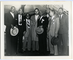 Thumbnail for Joe Louis (center) and Frederick M. Roberts (fourth from right) standing with a group of unidentified men in front of airplane