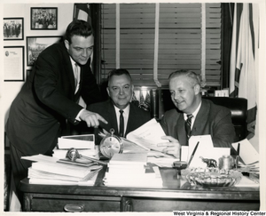 Photograph of Congressman Moore showing The Civil Rights Act of 1964 to two unidentified men