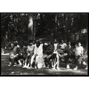 A Large group of youth sitting and waiting on benches at a camp