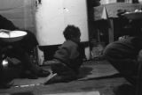 Young child with a puppy on the floor in front of a refrigerator in a small rural home in Autauga County, Alabama.