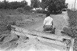 Man driving a tractor down a dirt road near Mount Meigs in Montgomery County, Alabama.