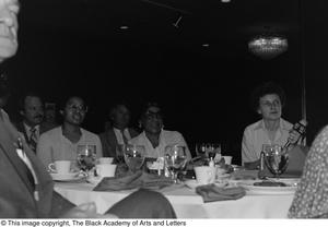 Photograph of a dining table with five unidentified individuals