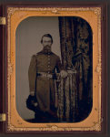 Thumbnail for [Captain John Wilson of Co. C, 8th Kentucky Infantry Regiment (Union), in uniform with sword; revolver and book rest on table]