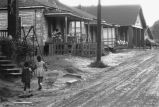 Children walking along dirt street.