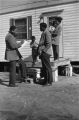 Recruiter standing outside a mobile home interviewing family.