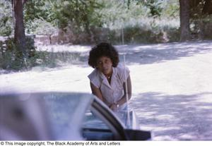 Photograph of a woman leaning towards the trunk of a vehicle