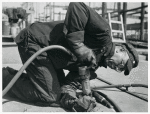 African American man kneeling and holding a drill